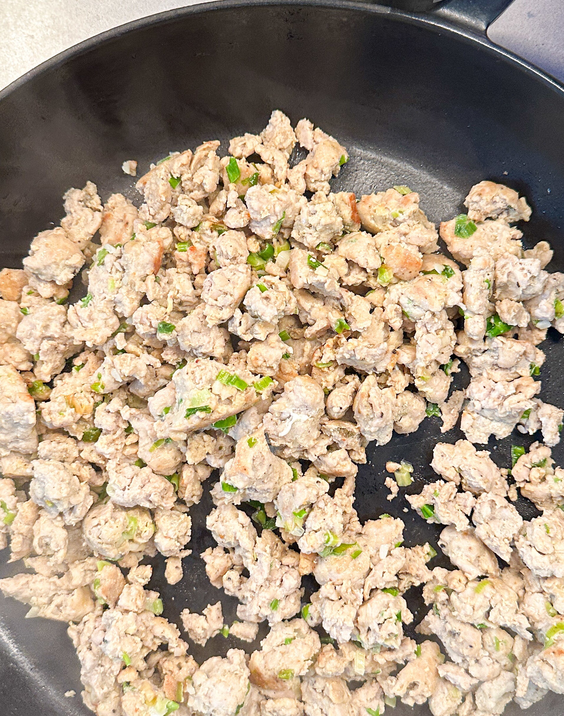 Ground turkey with herbs cooking in a skillet on a stovetop
