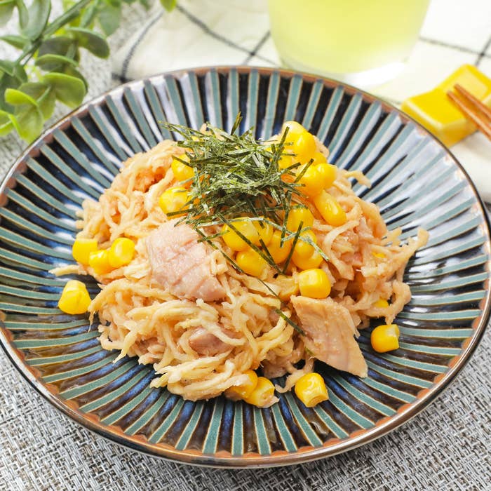 お皿に盛られたサラダ。トウモロコシ、刻み海苔がのっています。背景に飲み物と箸が見えます。