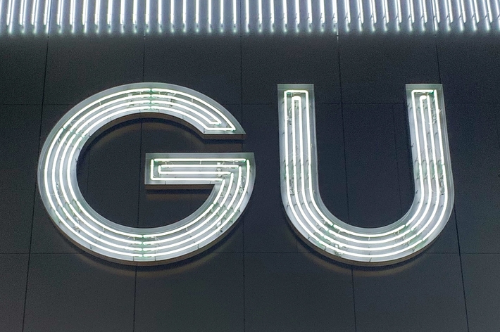 GUのネオン看板が夜の建物の外壁に取り付けられている。