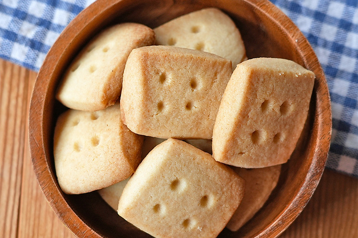 木製のボウルに入ったショートブレッドクッキー。背景にはチェック柄の布。