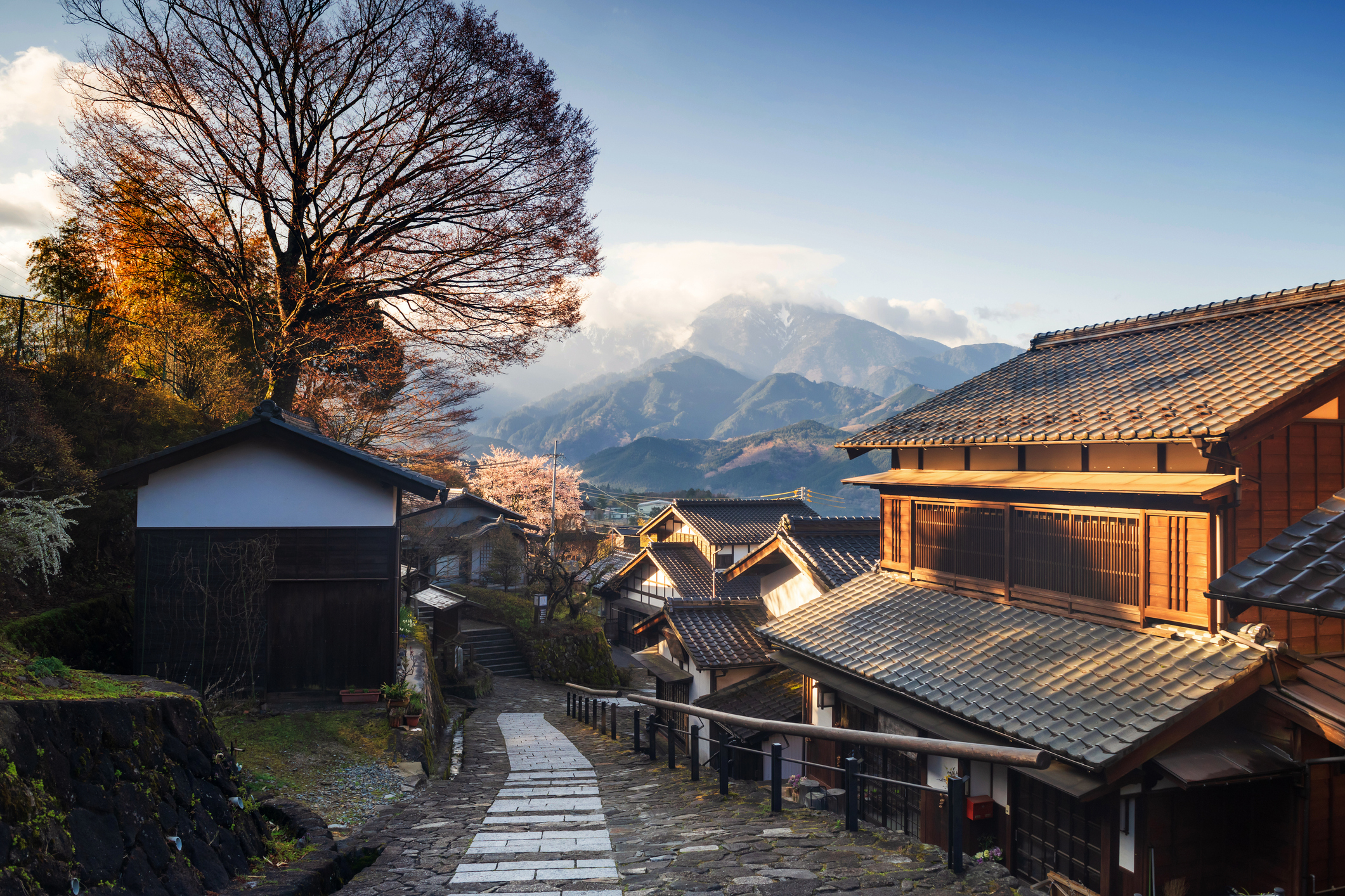 Scenic village with traditional houses, narrow paved path, and mountainous background under a clear sky