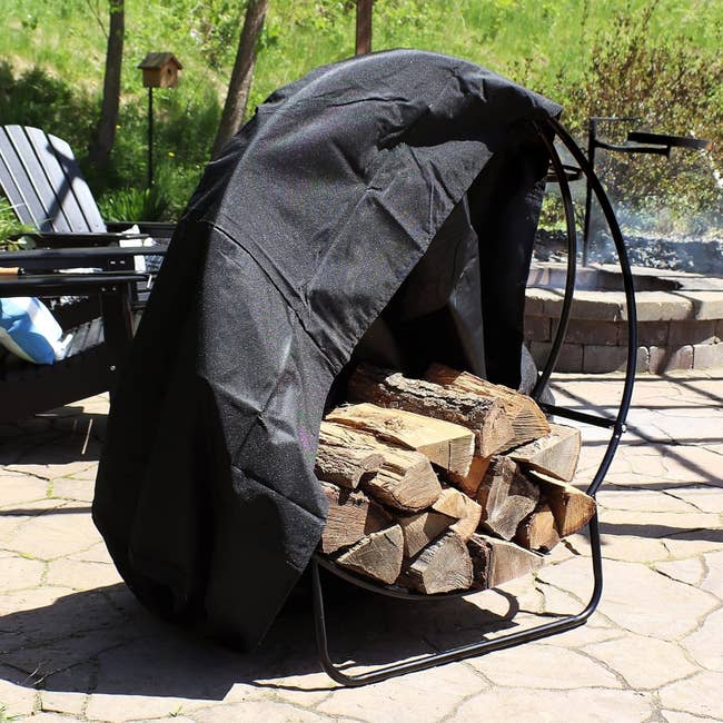 Firewood is neatly stacked connected a circular rack, covered with a achromatic tarp. The setup is situated connected a chromatic patio adjacent a fewer outdoor chairs