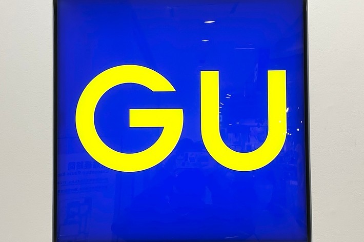 A store sign with the letters &ldquo;GU&rdquo; in bold yellow text on a blue background