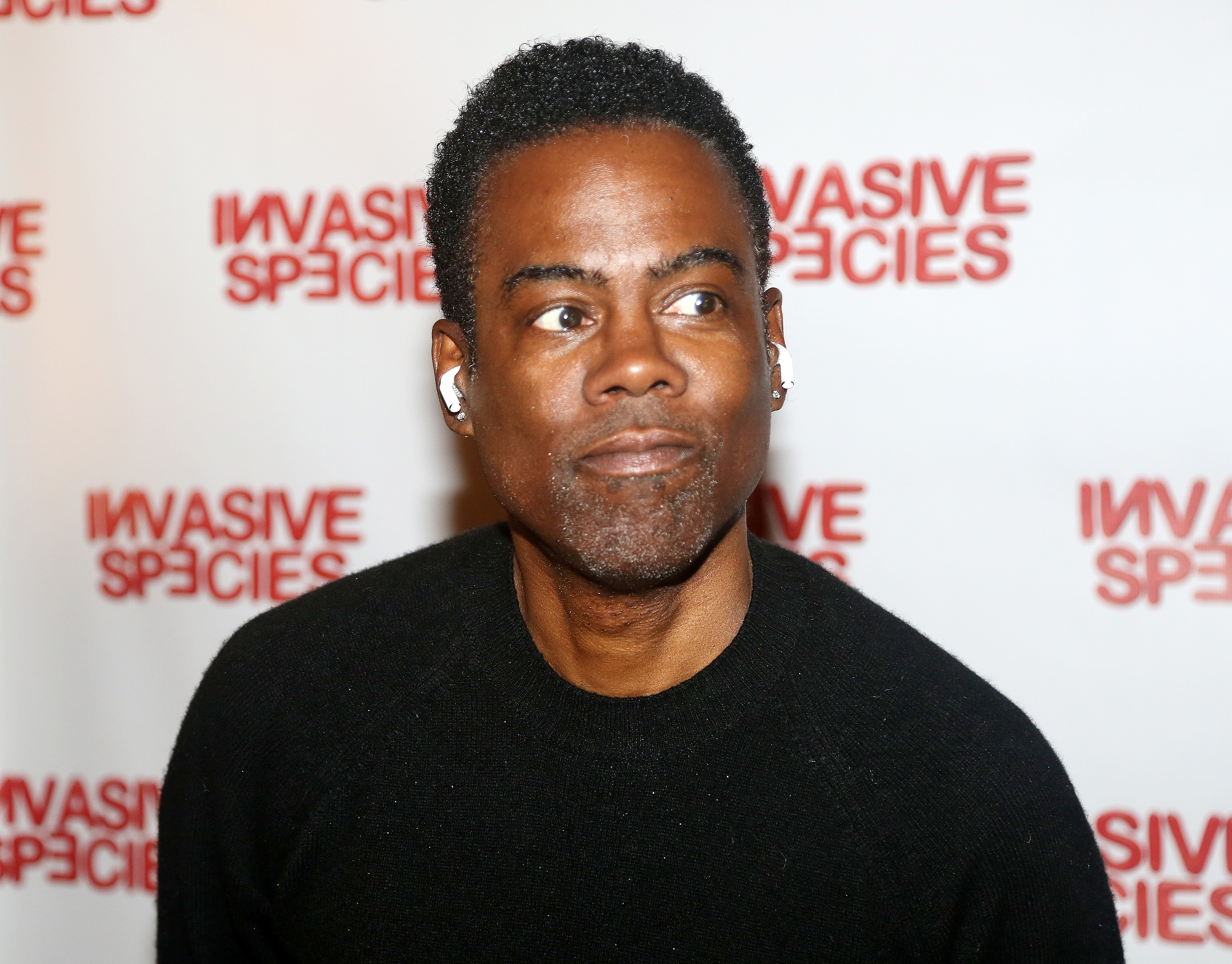 Chris Rock at an event for "Invasive Species," wearing a black top, looking slightly to the side