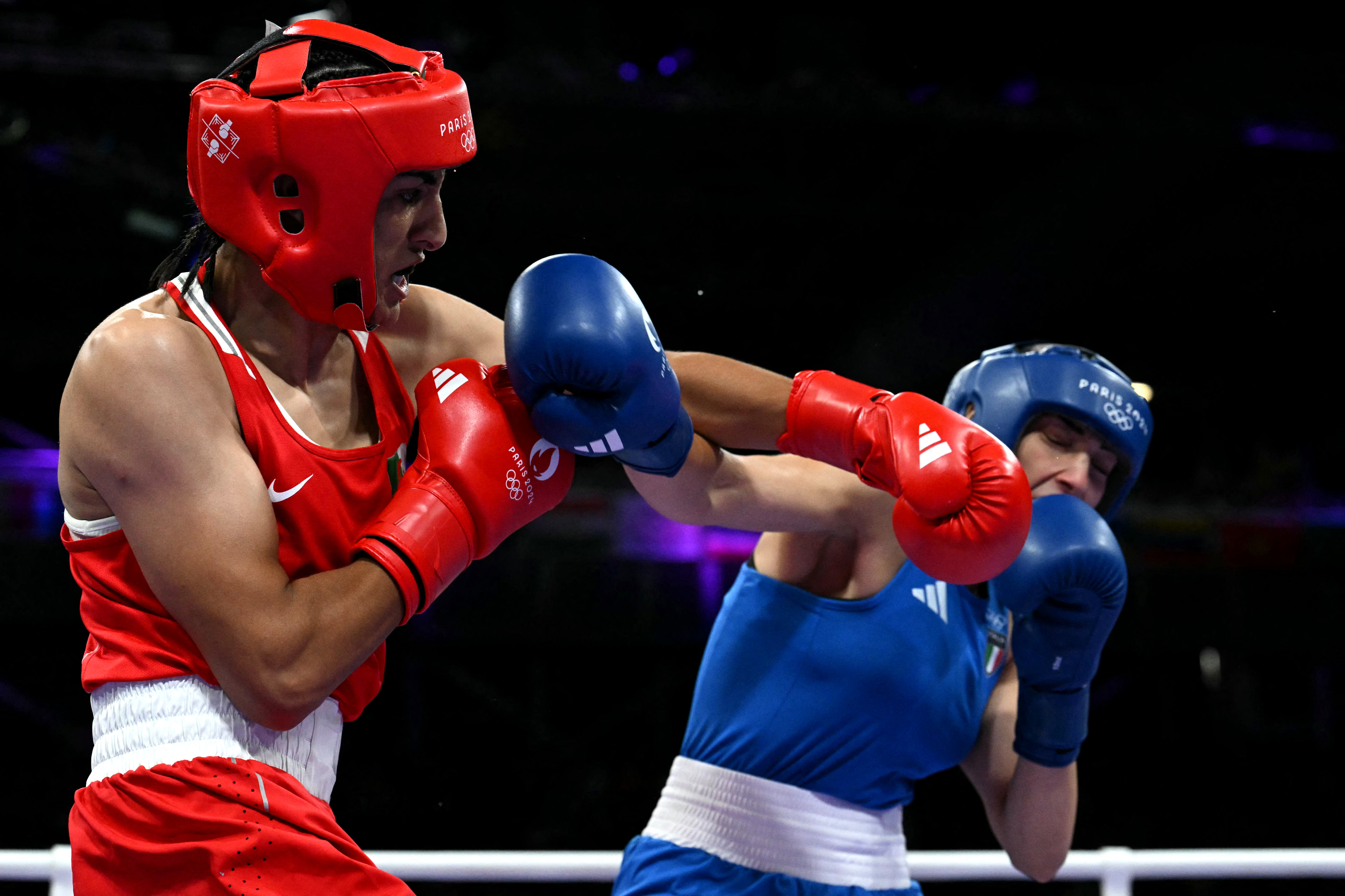 Two boxers in a match: one in a red kit delivering a punch to another in a blue kit