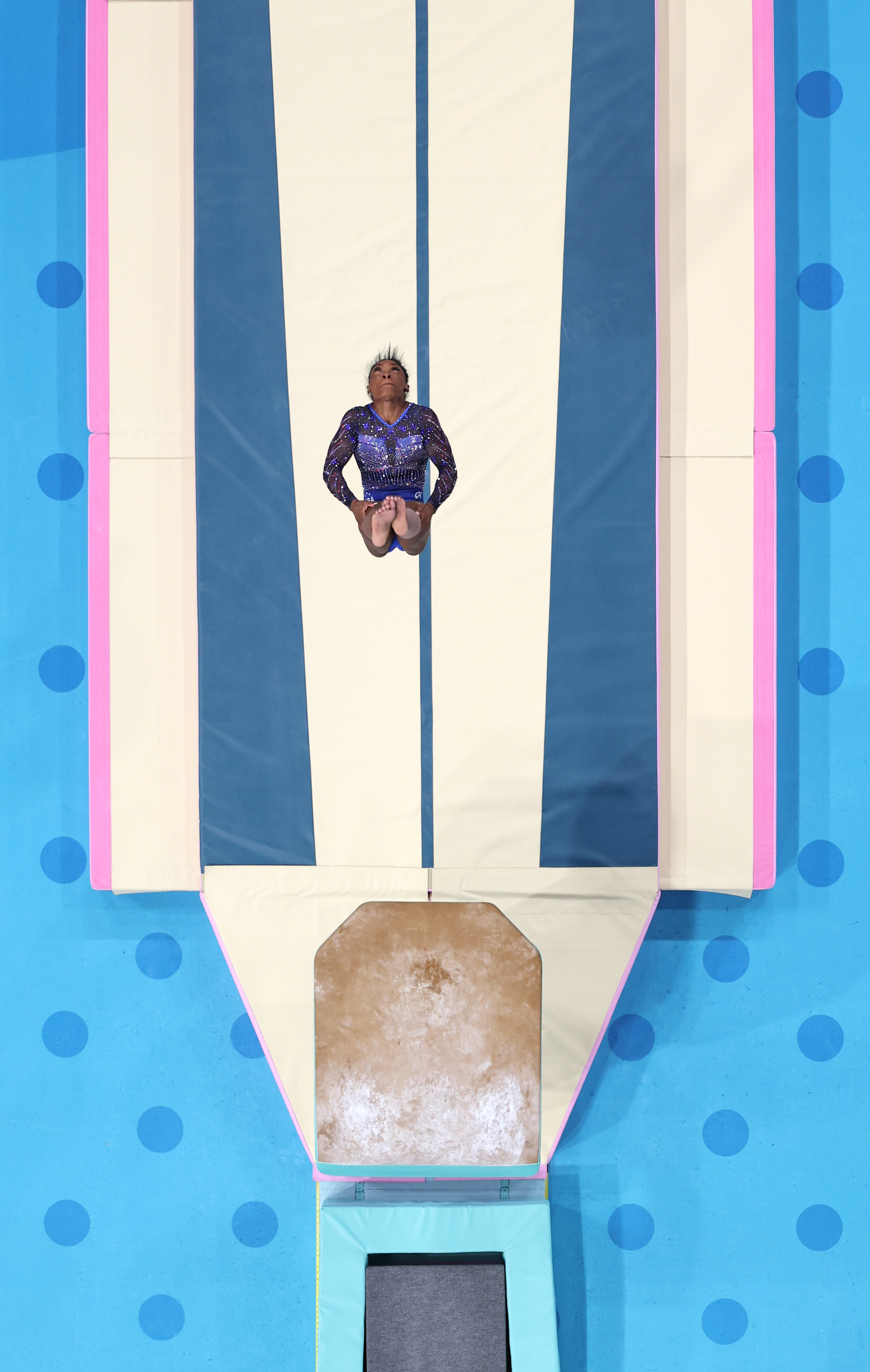 Gymnast Simone Biles prepares to perform on the vault, wearing a sparkly, long-sleeve leotard, during a competition