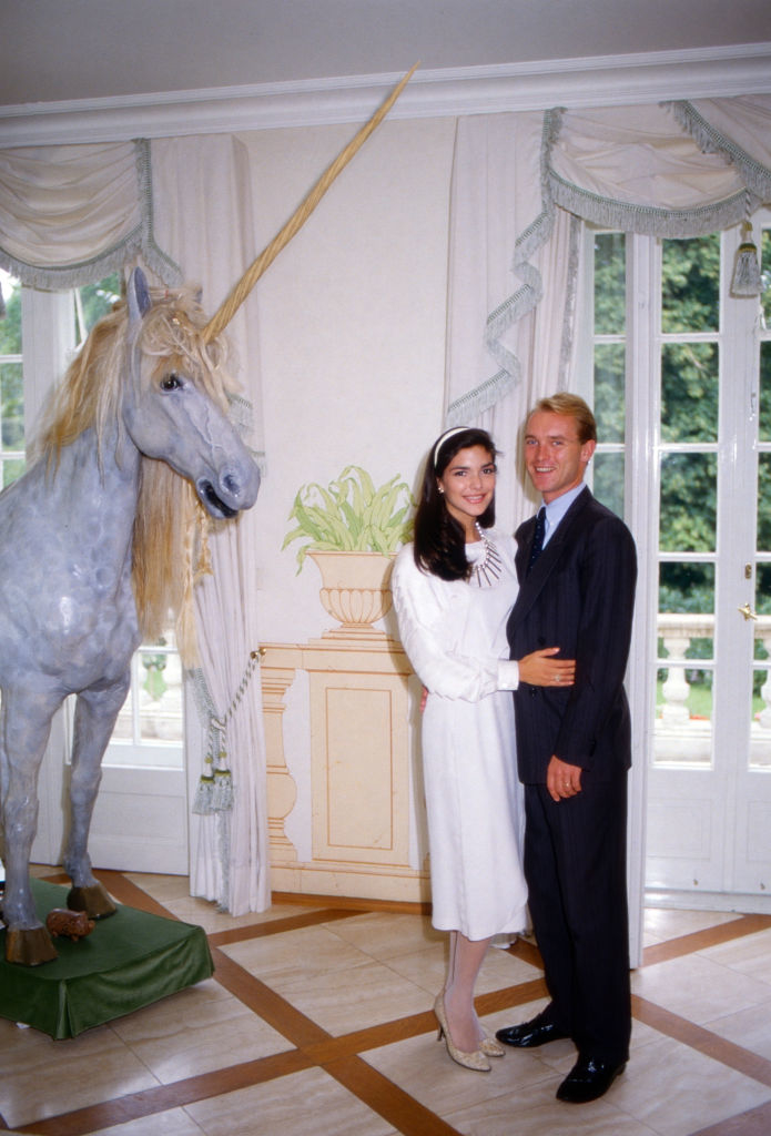 Laura and Carl elegantly dressed standing indoors next to a unicorn statue