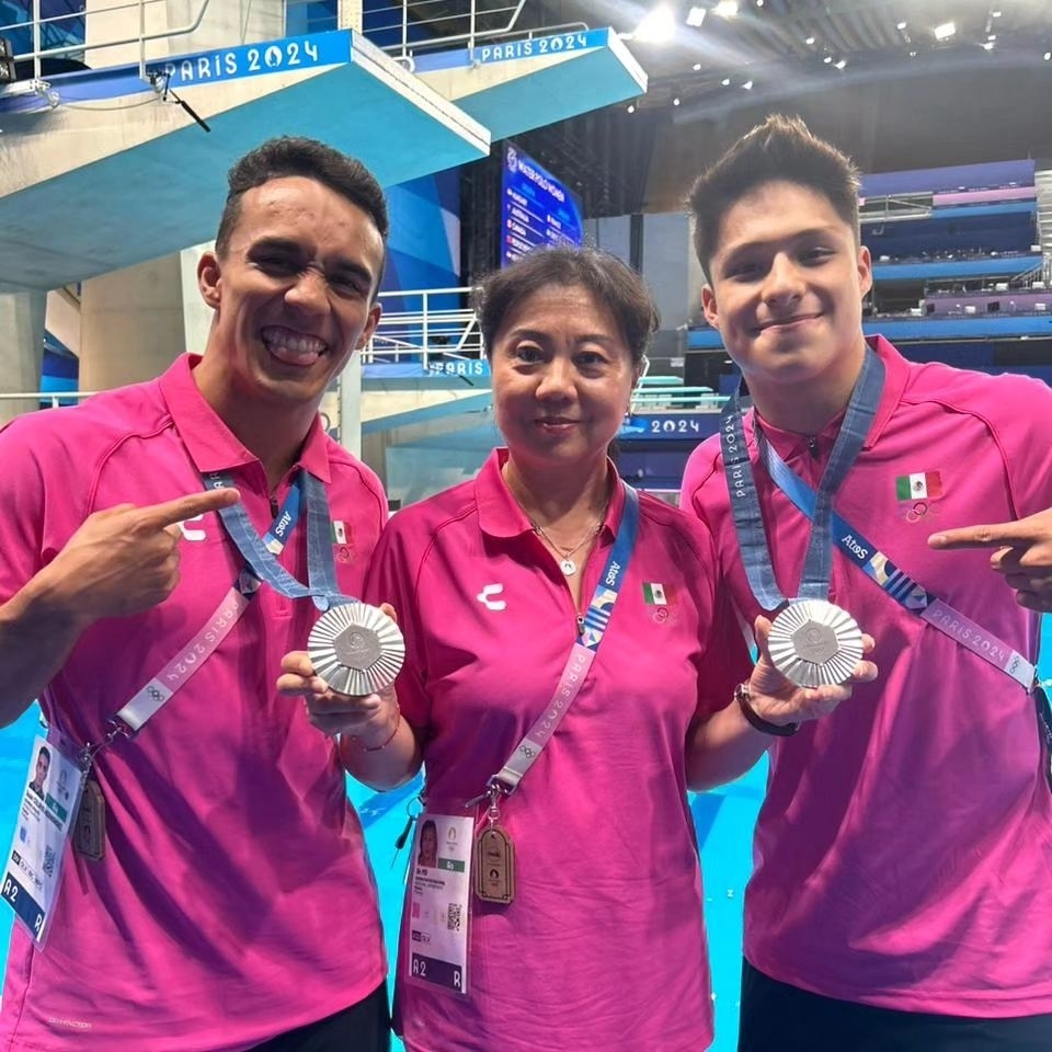 Dos atletas, Osmar Olvera y Kevin Berlín, y su entrenadora Ma Jin, posan sonrientes con medallas de plata en el evento París 2024