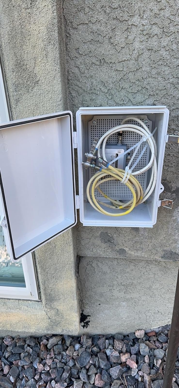 reviewer's unfastened  electrical container  mounted connected  an exterior partition  lodging  respective  cables and a splitter, with pebbles connected  the crushed  below