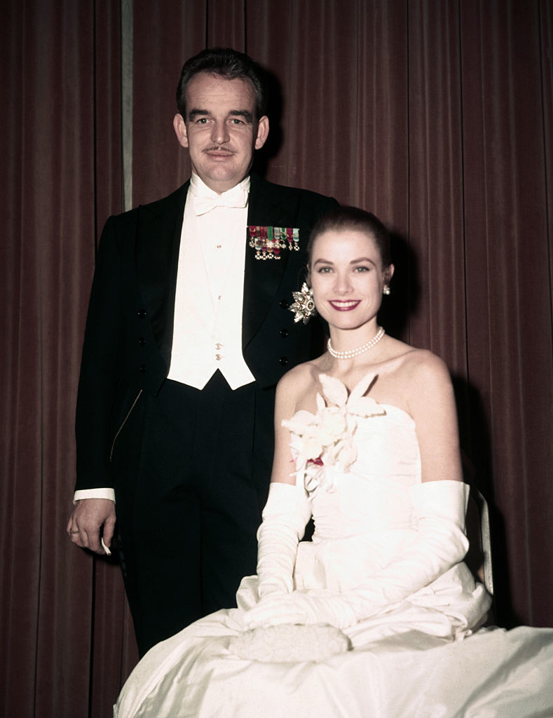 Prince Rainier III in a tuxedo and Grace Kelly in an elegant gown with gloves and pearl necklace at a formal event