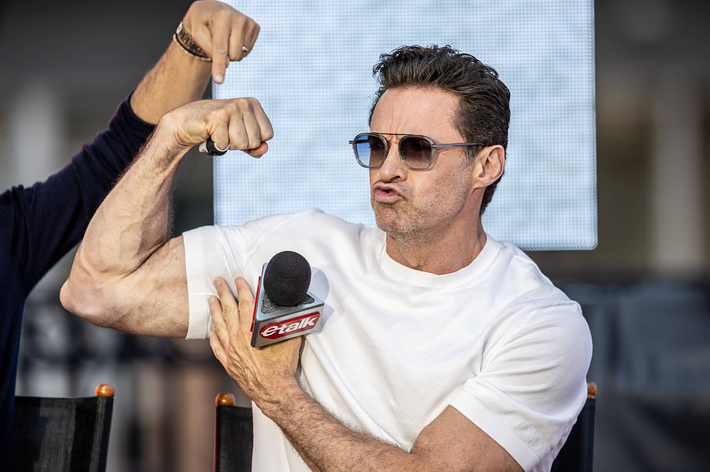 Hugh Jackman flexing his bicep during an interview