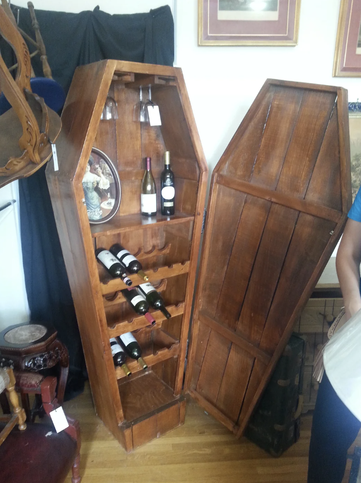 Reddit post titled "I found a coffin shaped wine rack at an antique store today," with a photo of a wooden, coffin-shaped wine rack holding several bottles