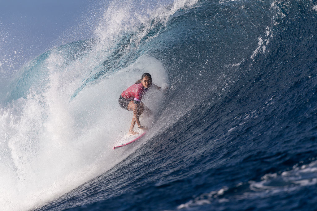 Surfer riding a large wave, half submerged in the tunnel of water