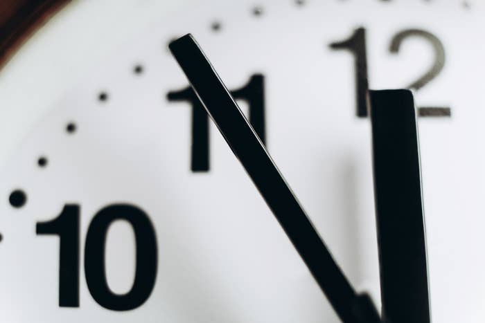 Close-up of a clock with its hands pointing at 11 and 12