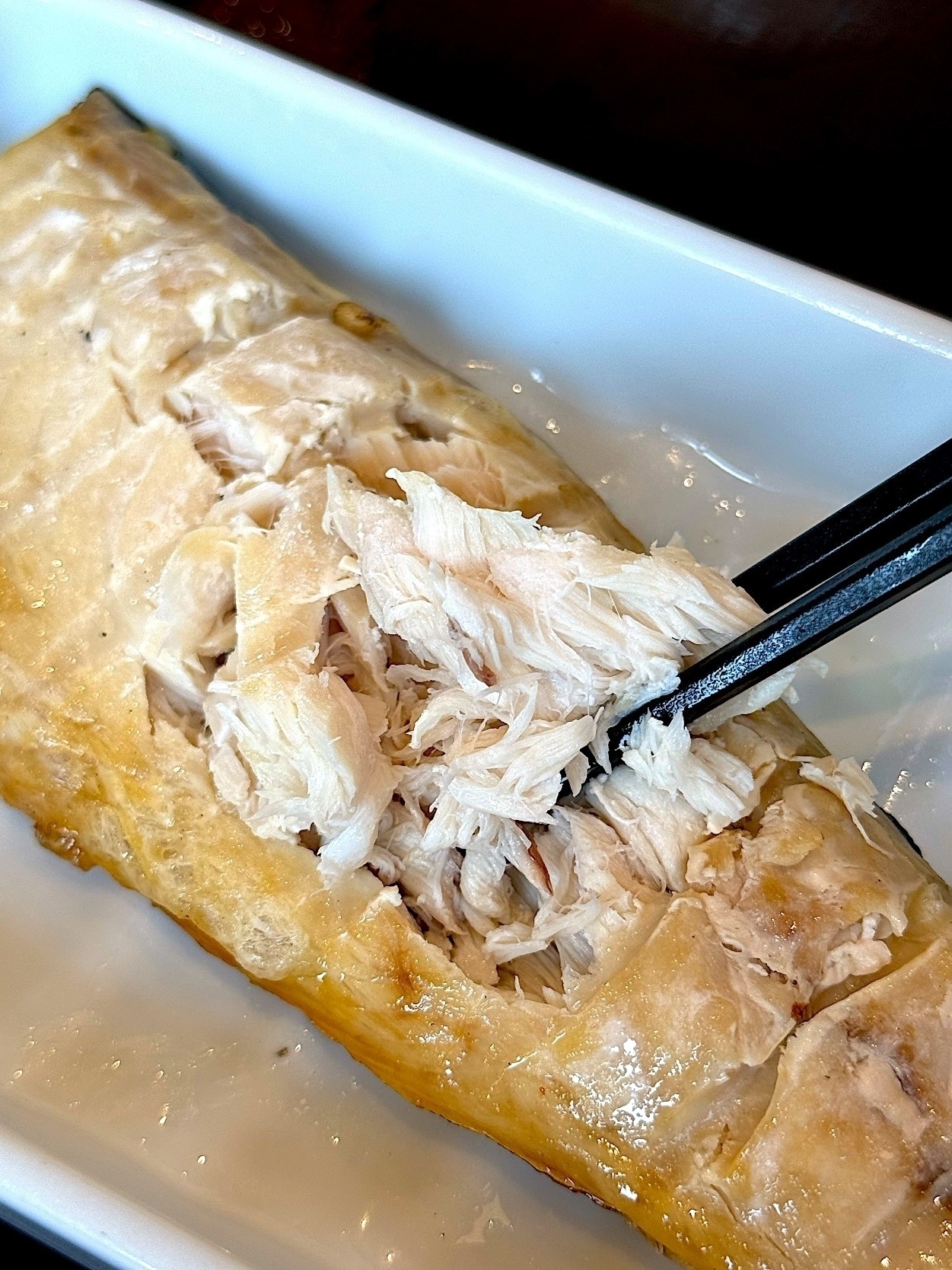 皿の中のシンプルな鶏肉の料理を箸でほぐしている様子。