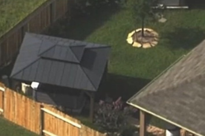 フェンスに囲まれた住宅と庭の航空写真。庭には木と小さな別棟が見えます。