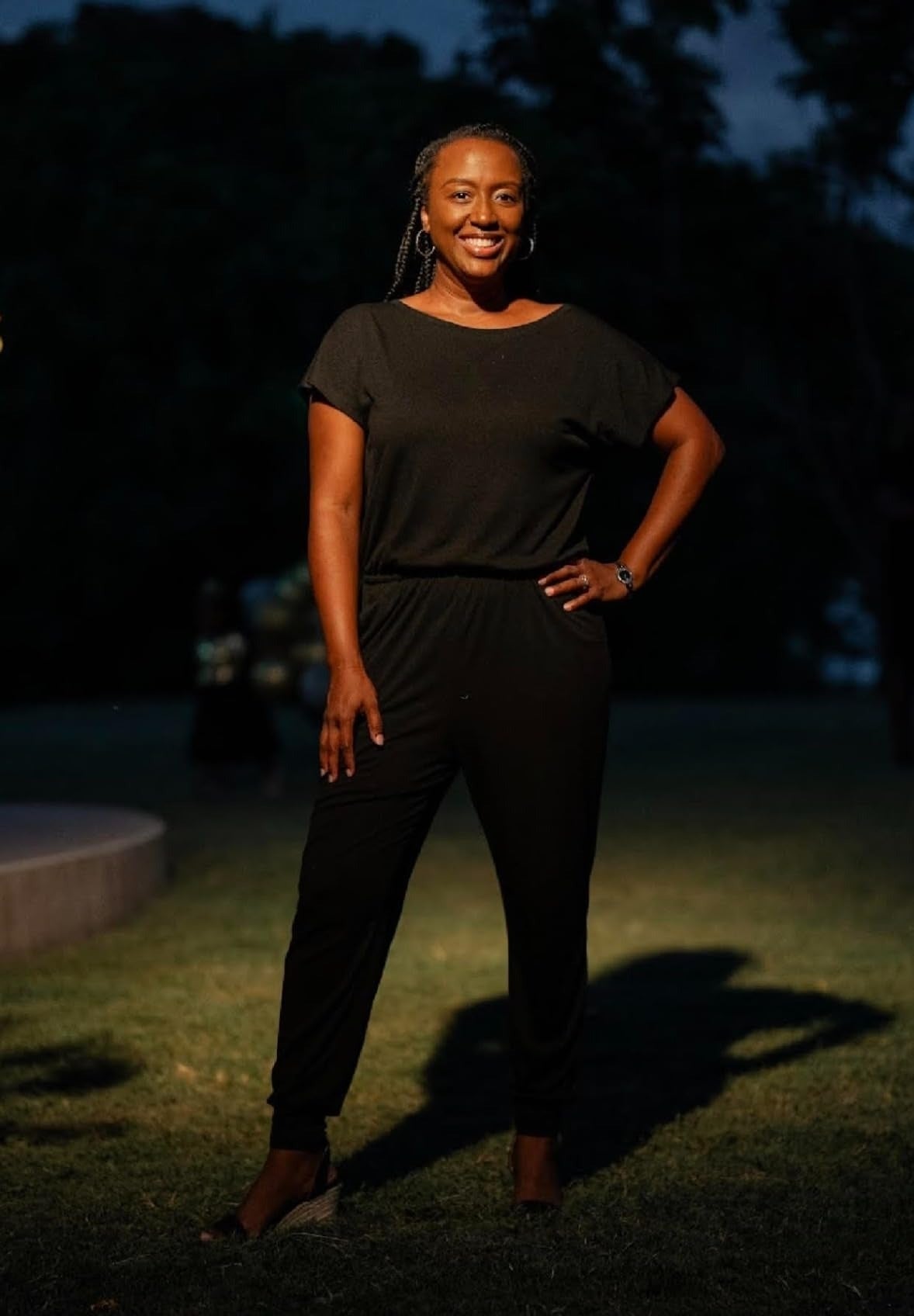 a reviewer lasting  outdoors astatine  night, wearing a stylish achromatic  jumpsuit