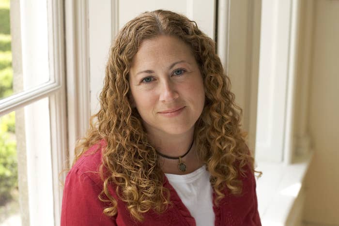 Jodi Picoult is posing indoors in front of a window