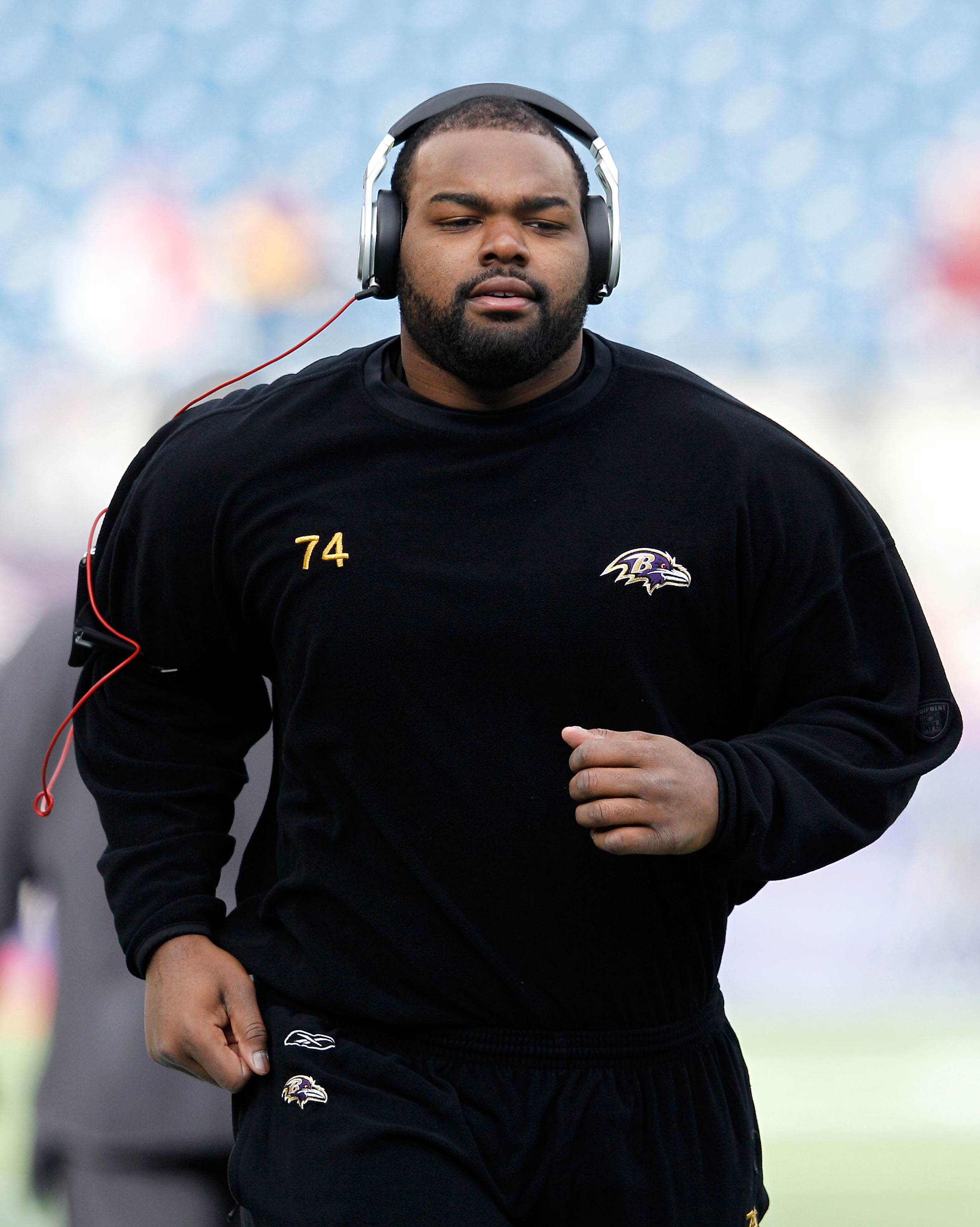 Michael Oher runs during warm-ups in athletic wear with headphones on