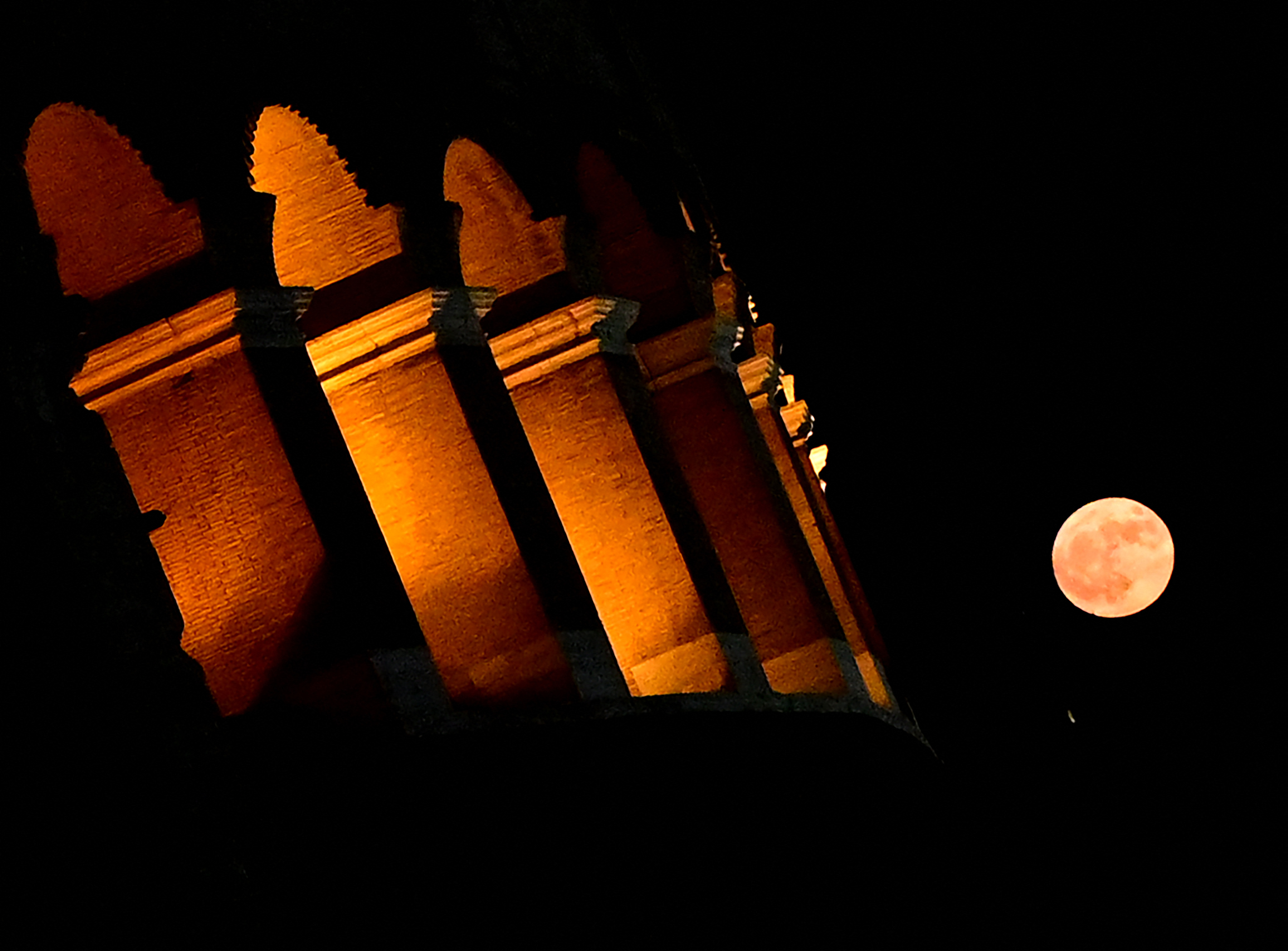 Night scene with the illuminated Leaning Tower of Pisa, Italy, and a full moon in the sky