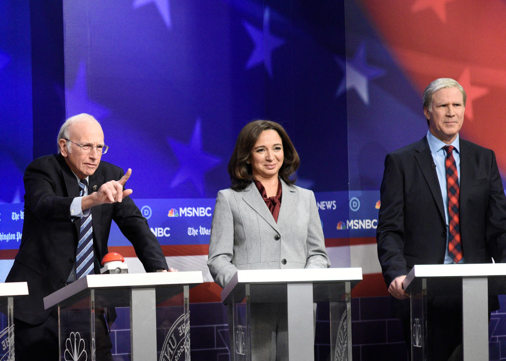 Actors portraying political figures, Larry David, Maya Rudolph, and Will Ferrell stand behind podiums during a comedy sketch