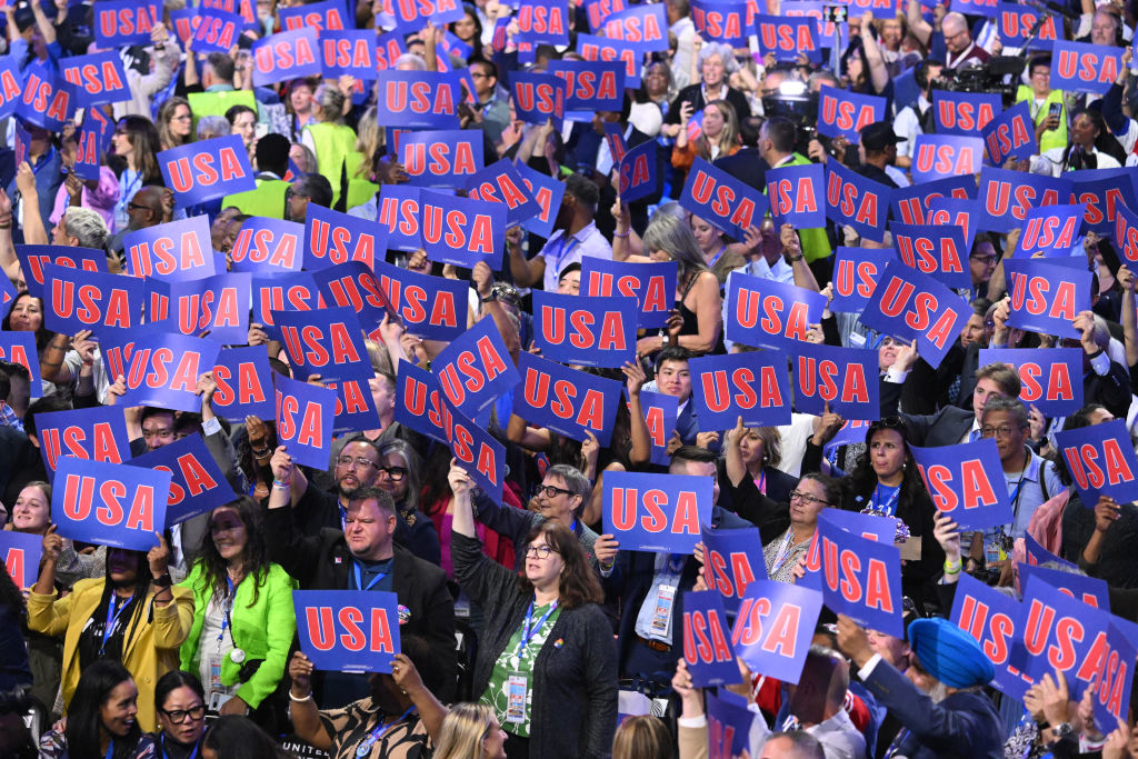 A large crowd holds up signs reading &quot;USA&quot; at what appears to be a political or patriotic event
