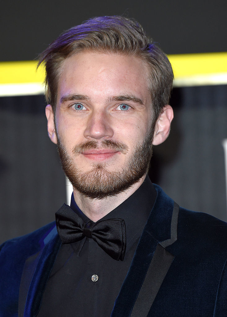 A man with a neat beard and dressed in a black suit with a bow tie poses for a photo at an event