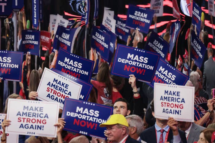 A crowd at a rally holds signs that say &quot;Mass Deportation Now!&quot; and &quot;Make America Strong Again!&quot; 2024 in large print