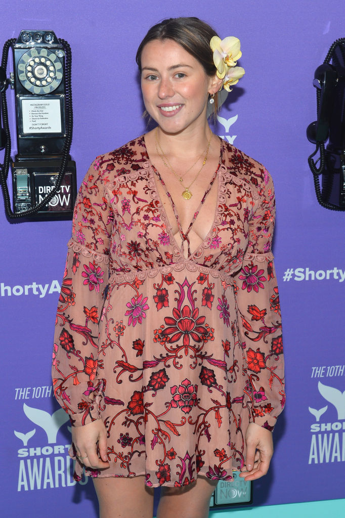 Woman in a floral-patterned dress with a plunging neckline at the Shorty Awards; she has a flower in her hair