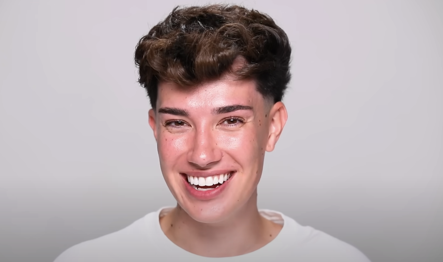 James Charles smiling at the camera with short hair, wearing a simple white top