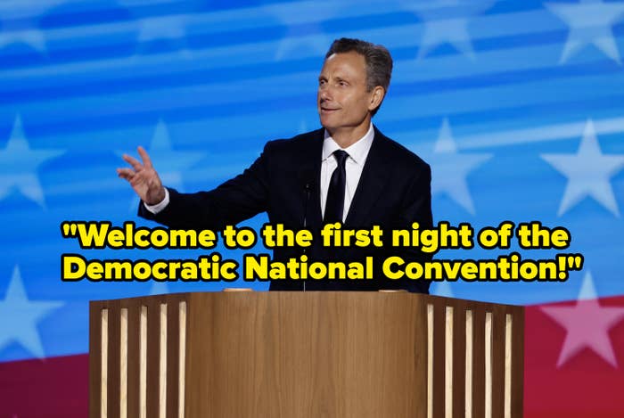 Tony in a suit gestures while speaking at a wooden podium. The background features a pattern of stars and stripes
