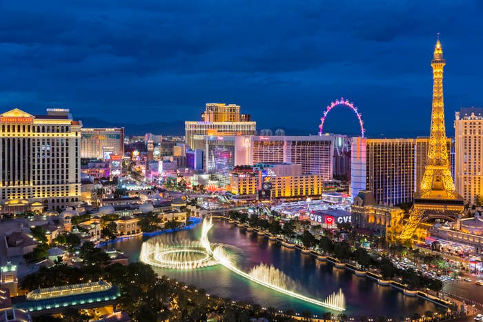 View of the Las Vegas Strip, featuring prominent landmarks like the Bellagio Fountains, Eiffel Tower replica, and the High Roller observation wheel at night
