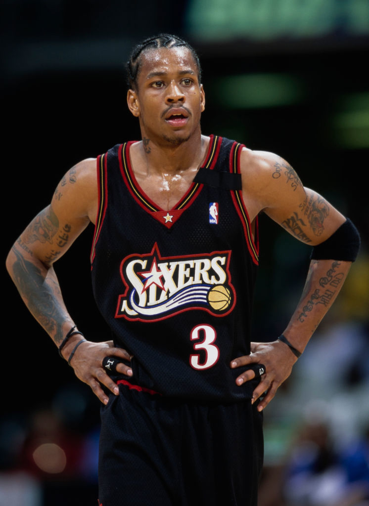 Allen Iverson wearing a black Philadelphia 76ers basketball jersey, standing with hands on hips during a game