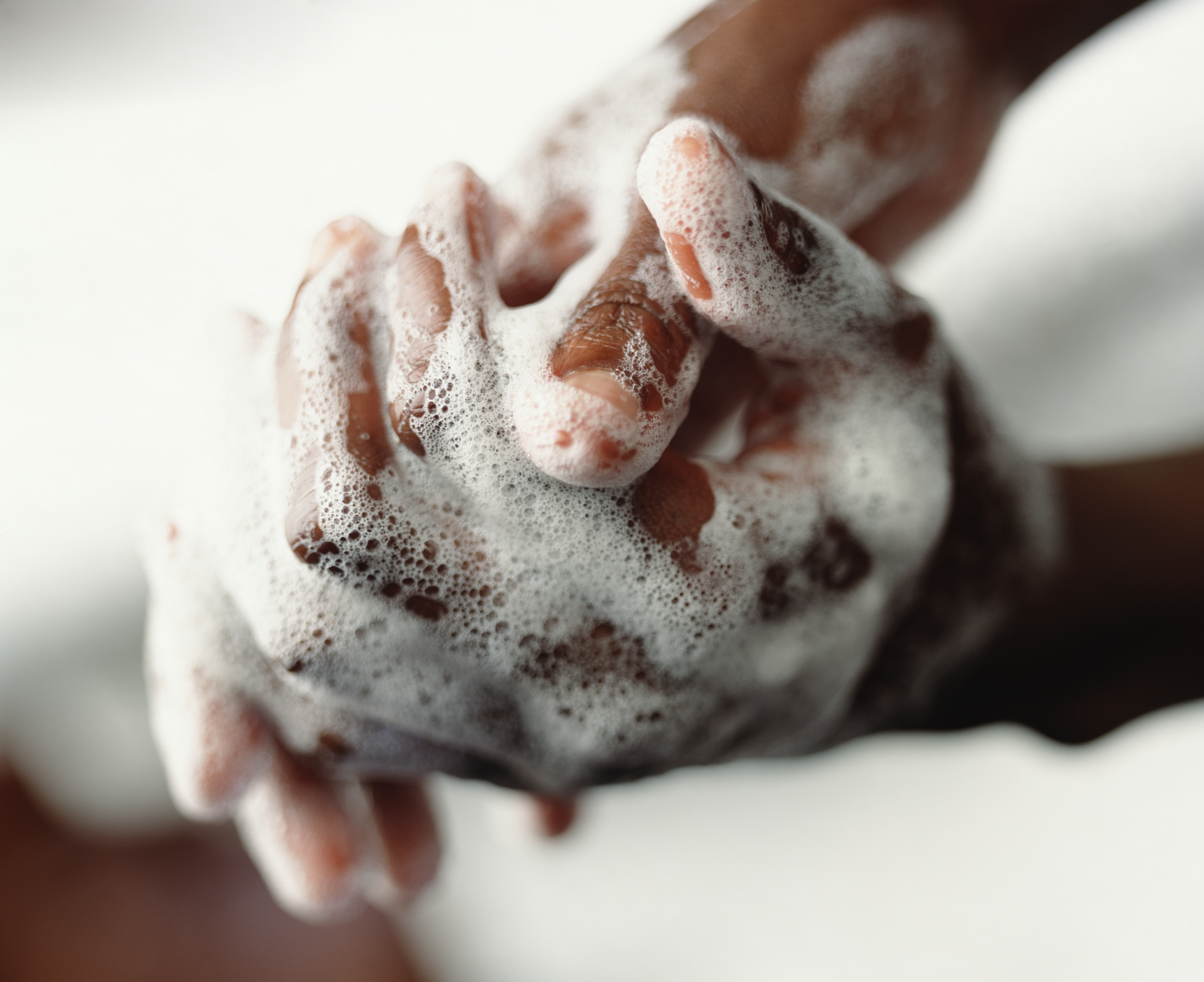 Two hands covered in soap lather are being washed