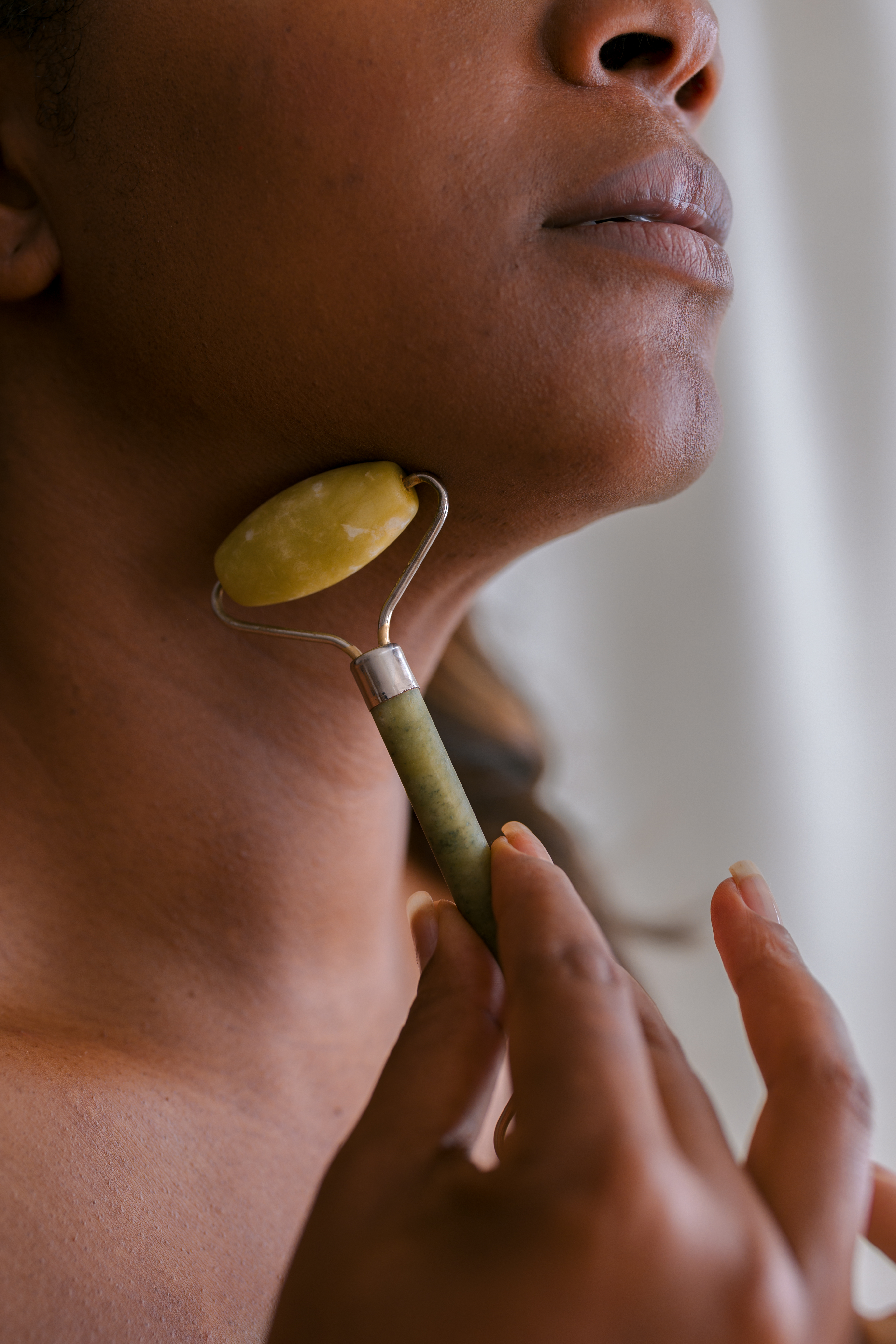 Close-up of a person using a jade roller on their jawline for facial massage