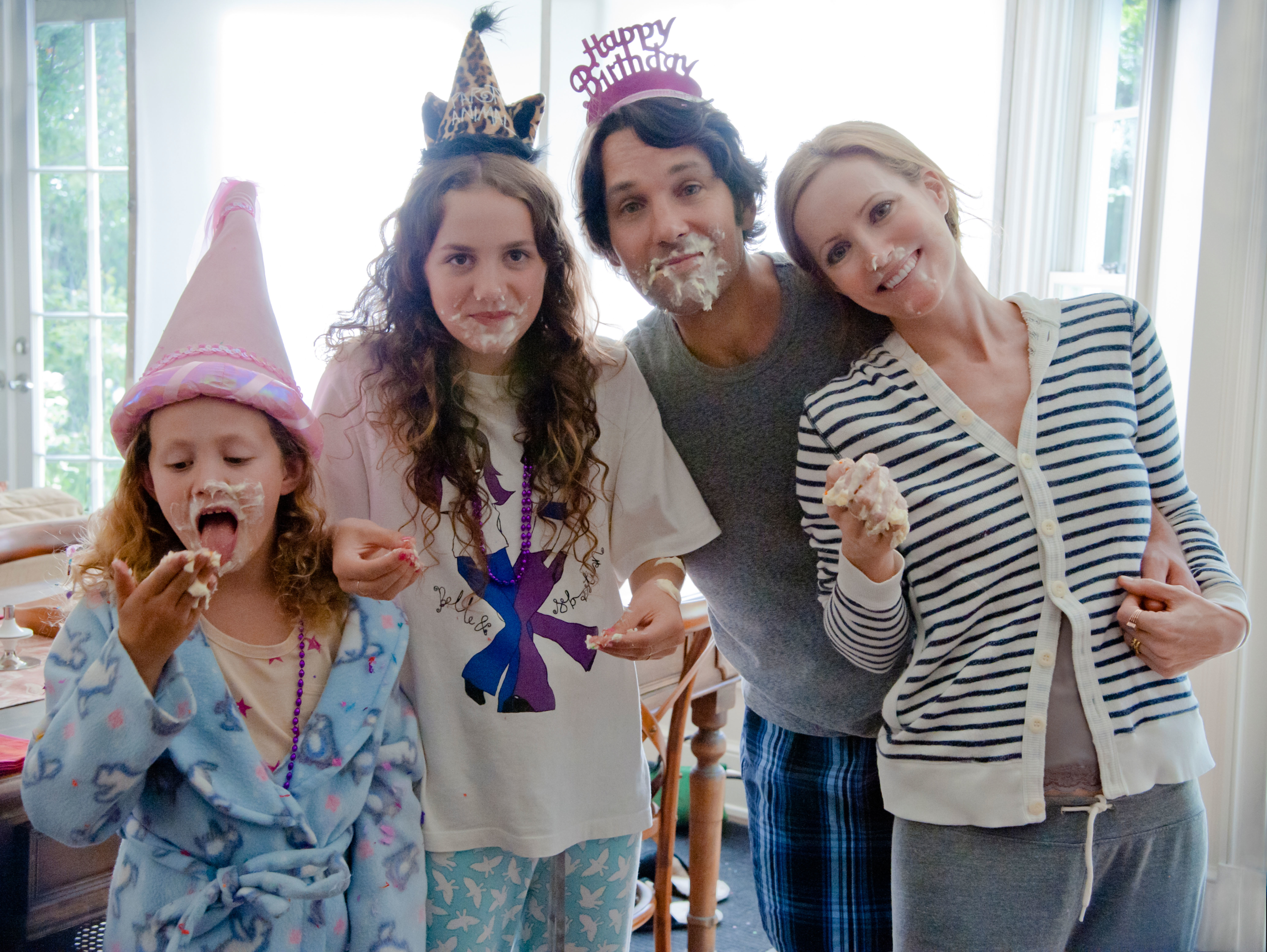 Iris Apatow, Maude Apatow, Paul Rudd, and Leslie Mann posing together with birthday cake on their faces in "This Is 40"