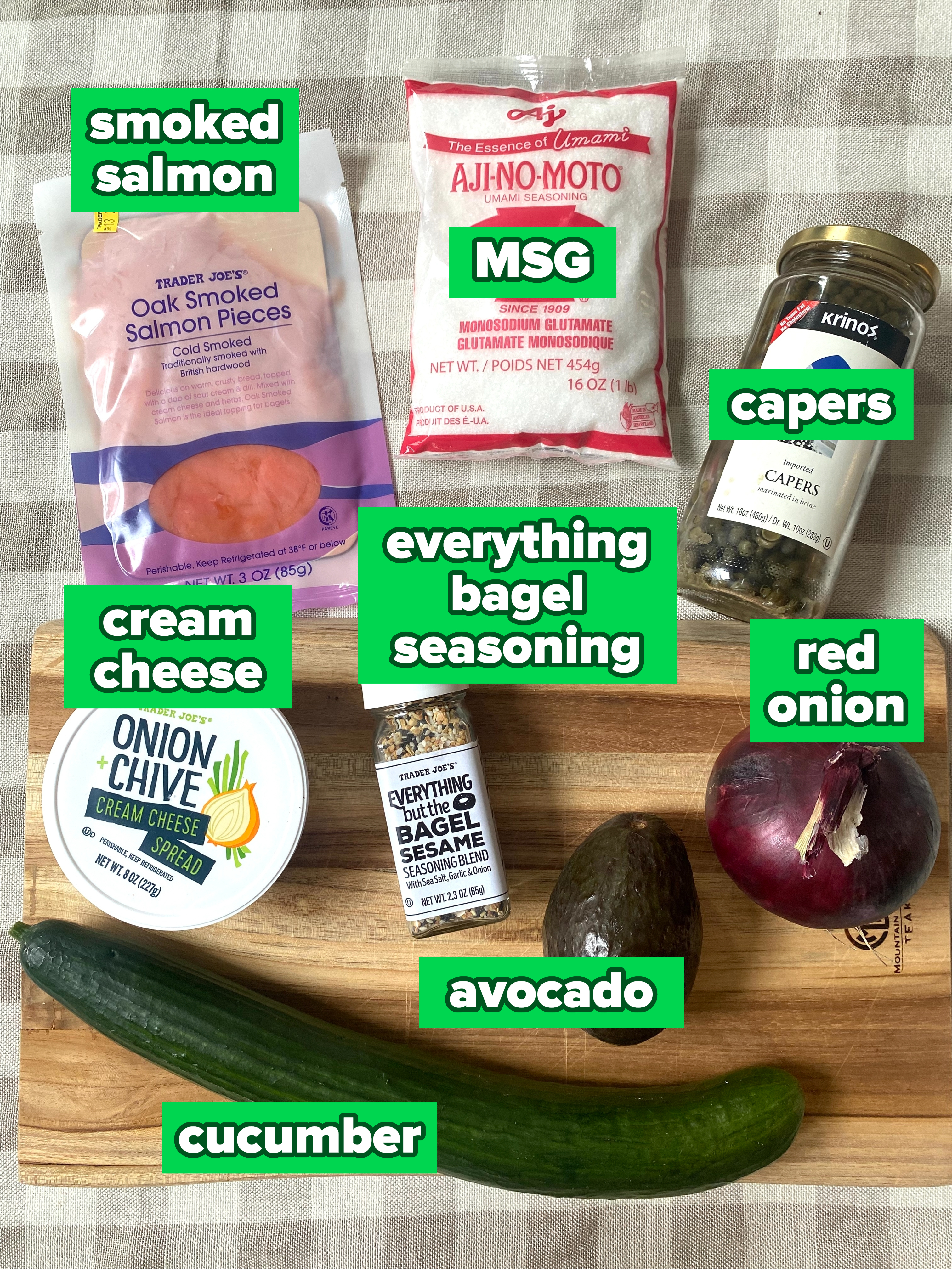 Various food items on a table, including avocado, cucumber, red onion, cream cheese, smoked salmon, capers, sesame seasoning, and MSG