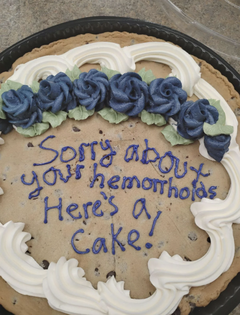 A cake with blue and white frosting has the message, "Sorry about your hemorrhoids. Here's a cake!" written on it