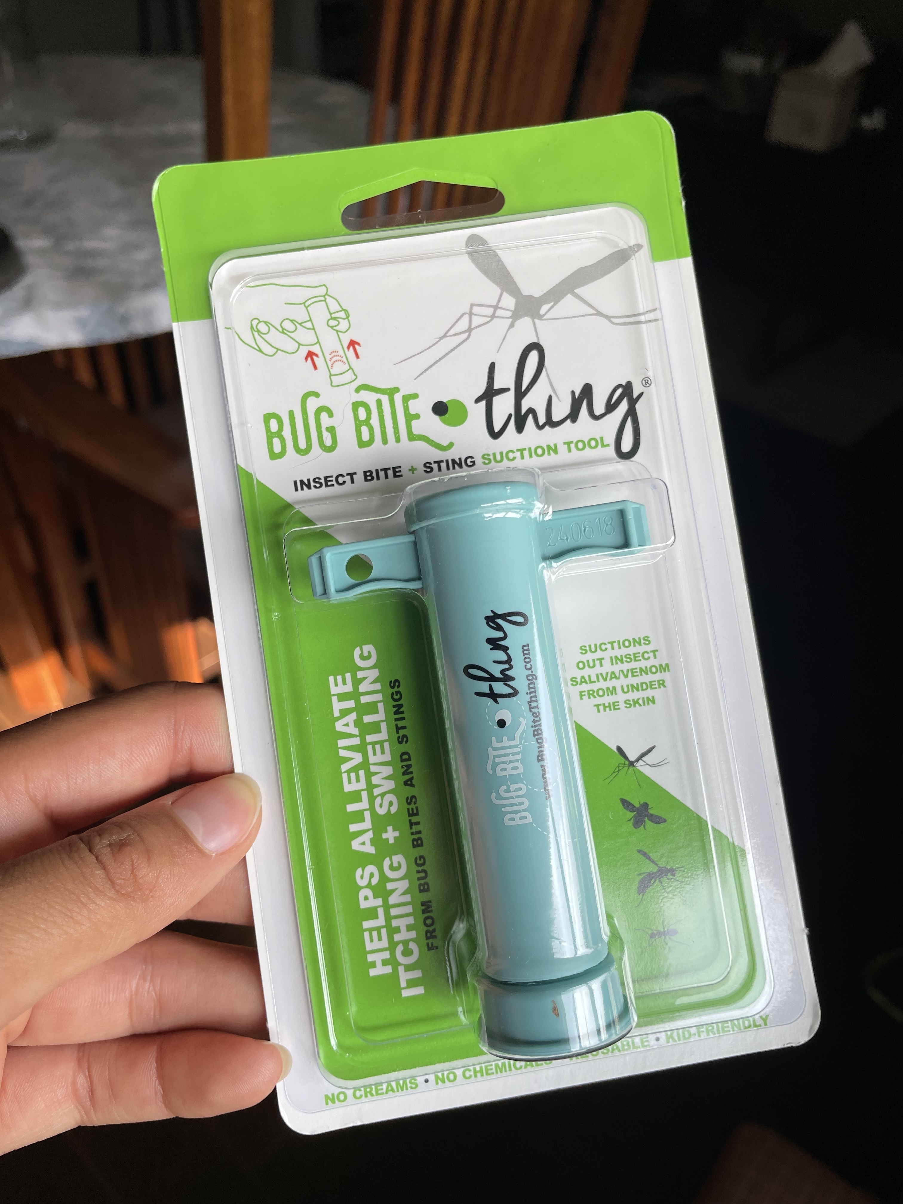 Hand holding packaging for the "Bug Bite Thing," an insect bite and sting suction tool that helps alleviate itching and swelling