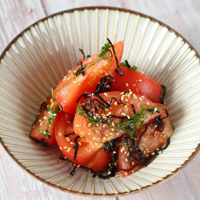 トマトのスライスと塩昆布、ゴマが盛り付けられた美しいサラダ。