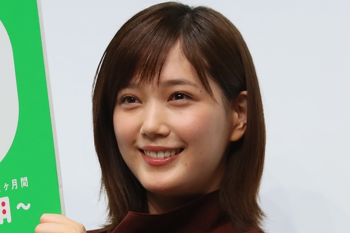 女性が微笑みながらパネルを持っている。