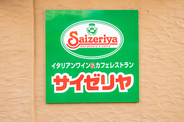 壁に掛けられたサイゼリヤの看板。「イタリアンワイン &amp; カフェレストラン サイゼリヤ」と書かれています。