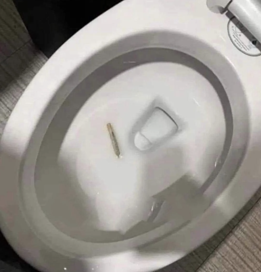 A single cigarette butt is discarded in a toilet bowl