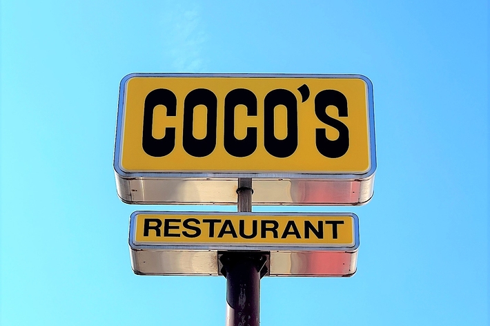 青空の下にある「COCO&rsquo;S RESTAURANT」の看板。