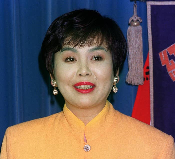 女性が黄色のジャケットを着て、笑顔でカメラを見ています。人物の名前はわかりません。