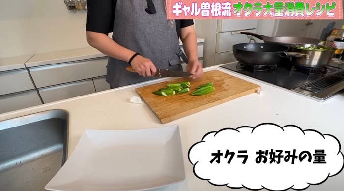 キッチンで料理をしている人がオクラを好みの量に切っている。