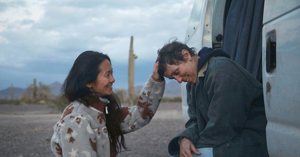 Chloe Zhao and Frances McDormand share a light moment; Zhao touches McDormand's head as they stand next to a vehicle in a desert landscape