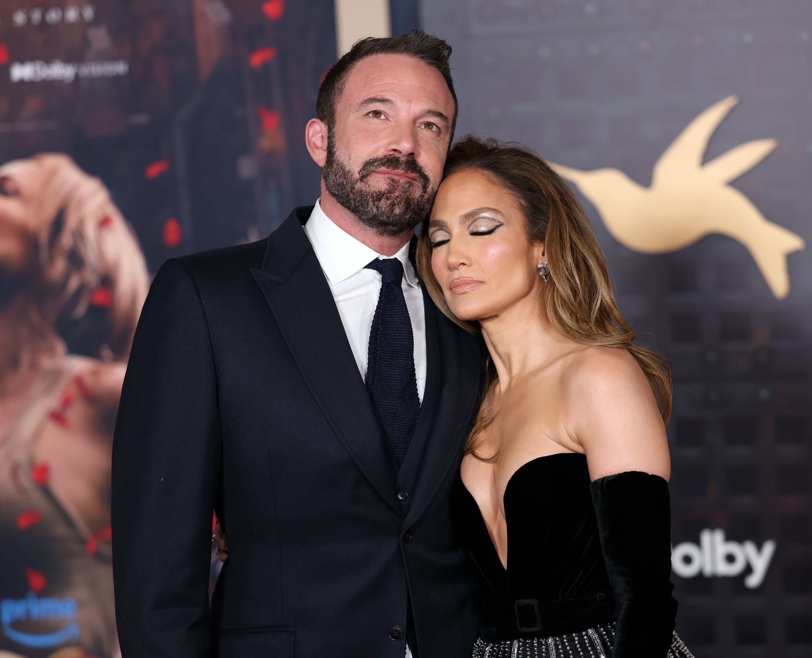 Ben Affleck and Jennifer Lopez pose together on the red carpet. Jennifer wears a strapless gown and Ben is dressed in a suit