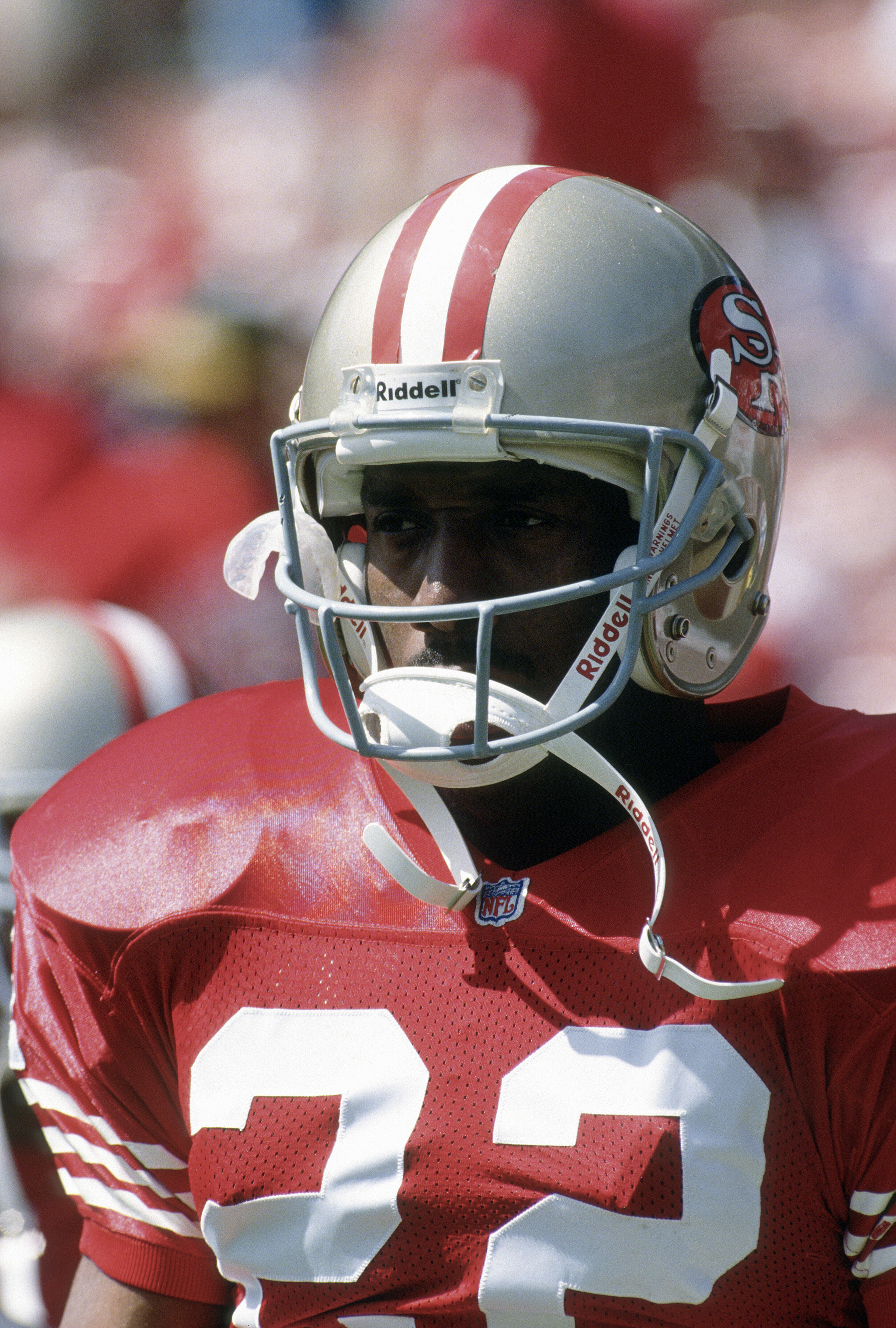 A football player wearing a San Francisco 49ers uniform and helmet, standing on the field during a game