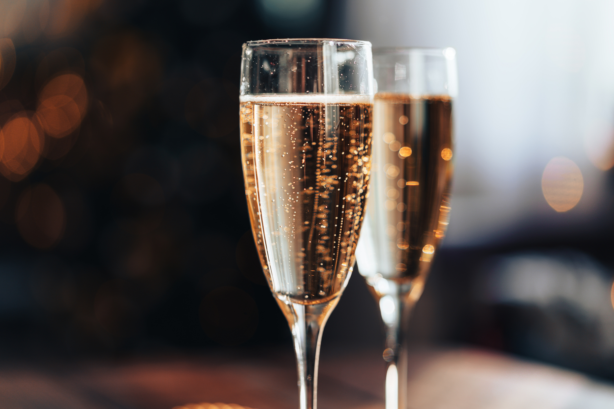 Two glasses filled with sparkling wine or champagne, set on a table with a blurred background
